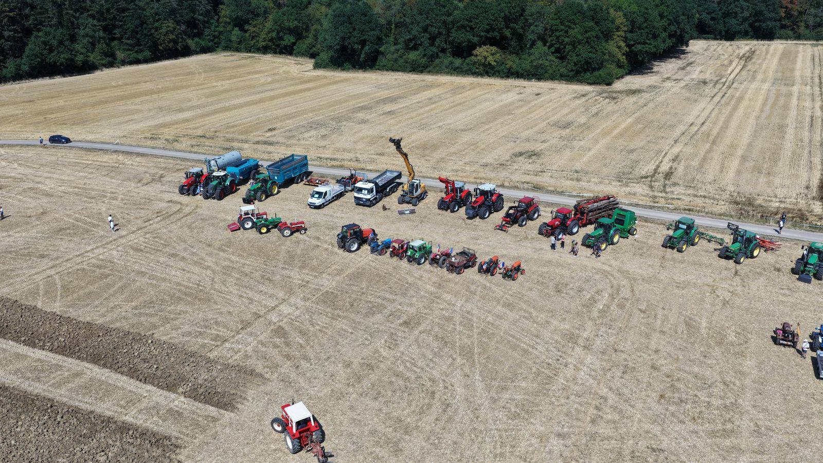Tracteurs alignés dans un champ moissonné vus du ciel